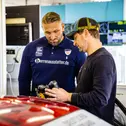 Ex-Meister Robert Renauer erklärt Kevin Kuske das Lenkrad seines Porsche 911 GT3 R