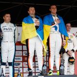 Die Ukrainer Konstantin Gutsul (3. v.l.) und Ivan Peklin (4. v.l.) feiern ihren Sieg im GT60 powered by Pirelli zusammen mit den zweitplatzierten Jannes Fittje (1. v.l.) und Friedel Bleifuss (2. v.l.) sowie Jay Mo Härtling (2. v.r.) und Julian Hanses (1. 